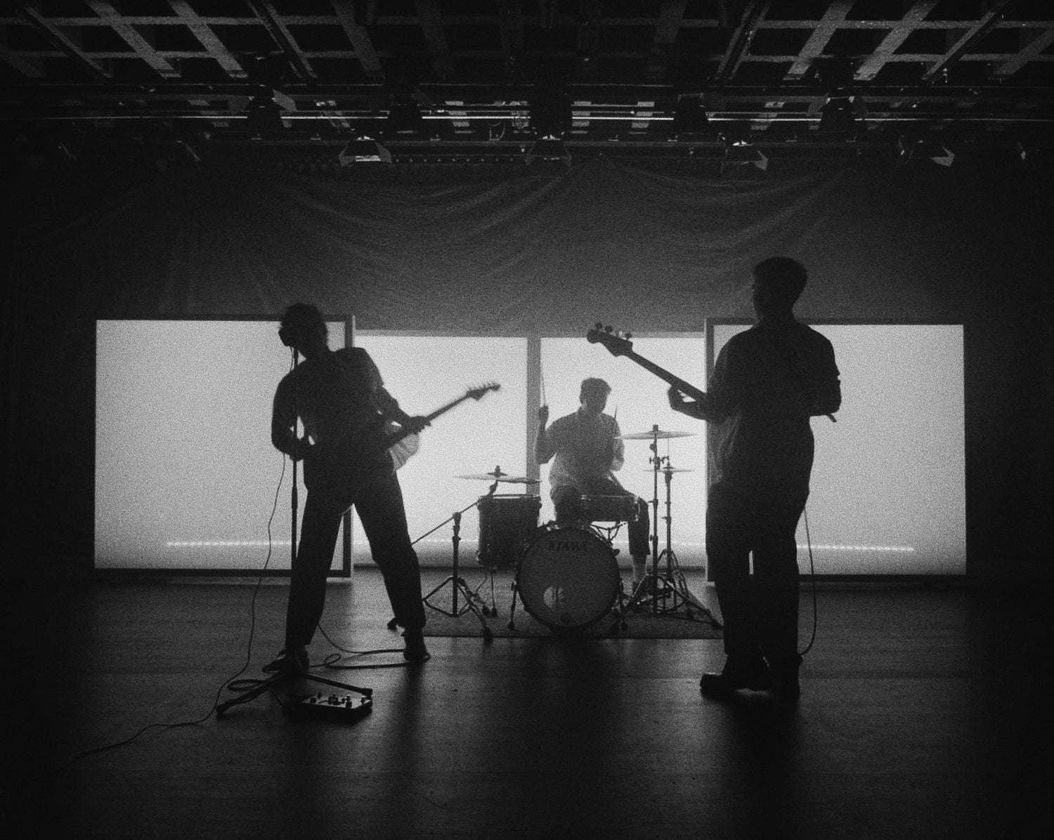 Silhouettes of a band playing music on a stage with instruments.